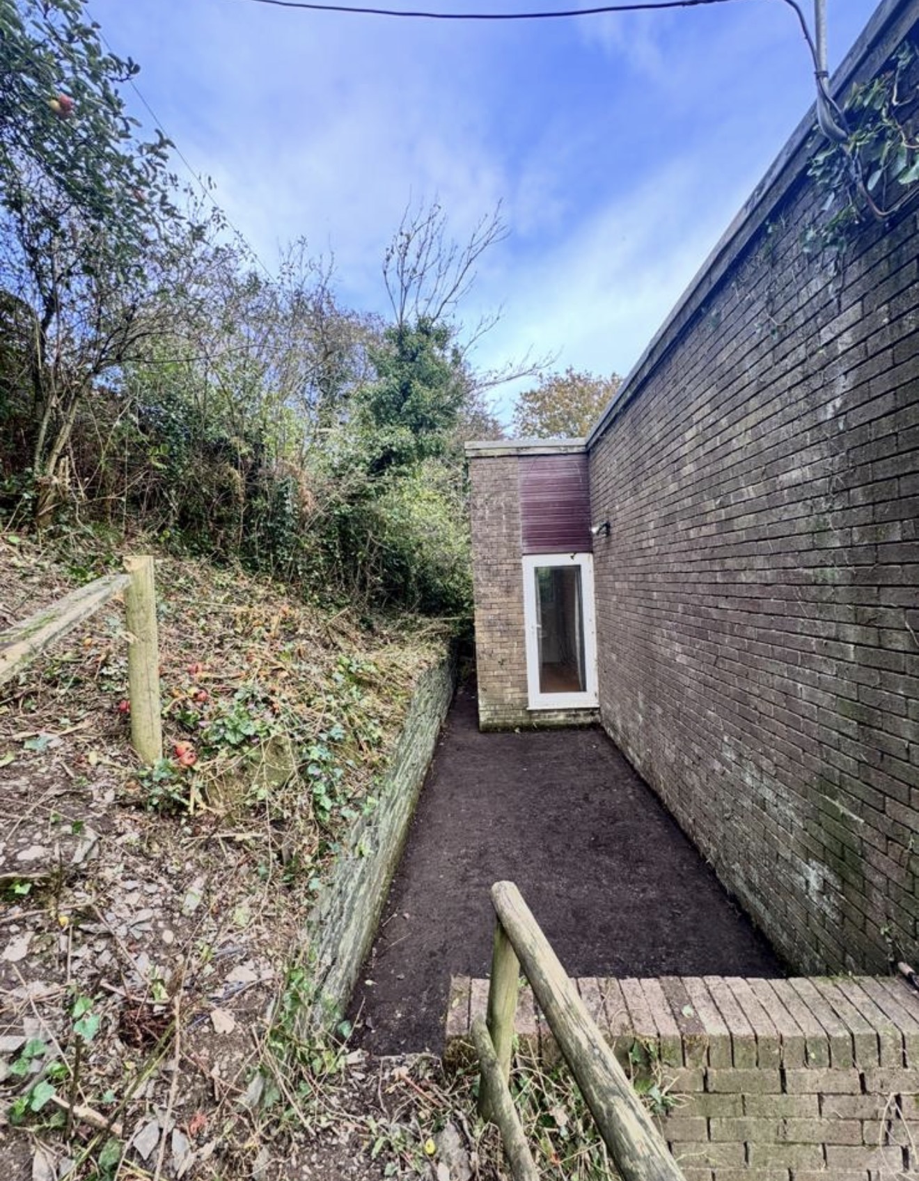 Cleared access route beside a building after bramble removal
